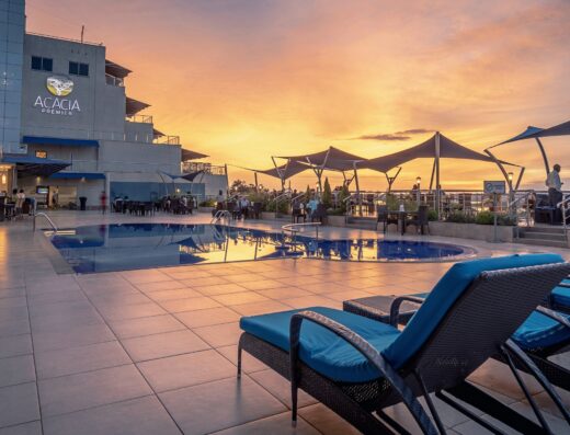 An image showcasing a swimming pool and Acacia Premier Hotel signage